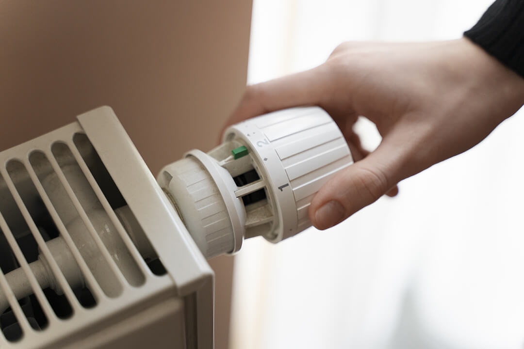 Picture of someone turning down a radiator to save the cost of gas in a combi boiler central heating system.
